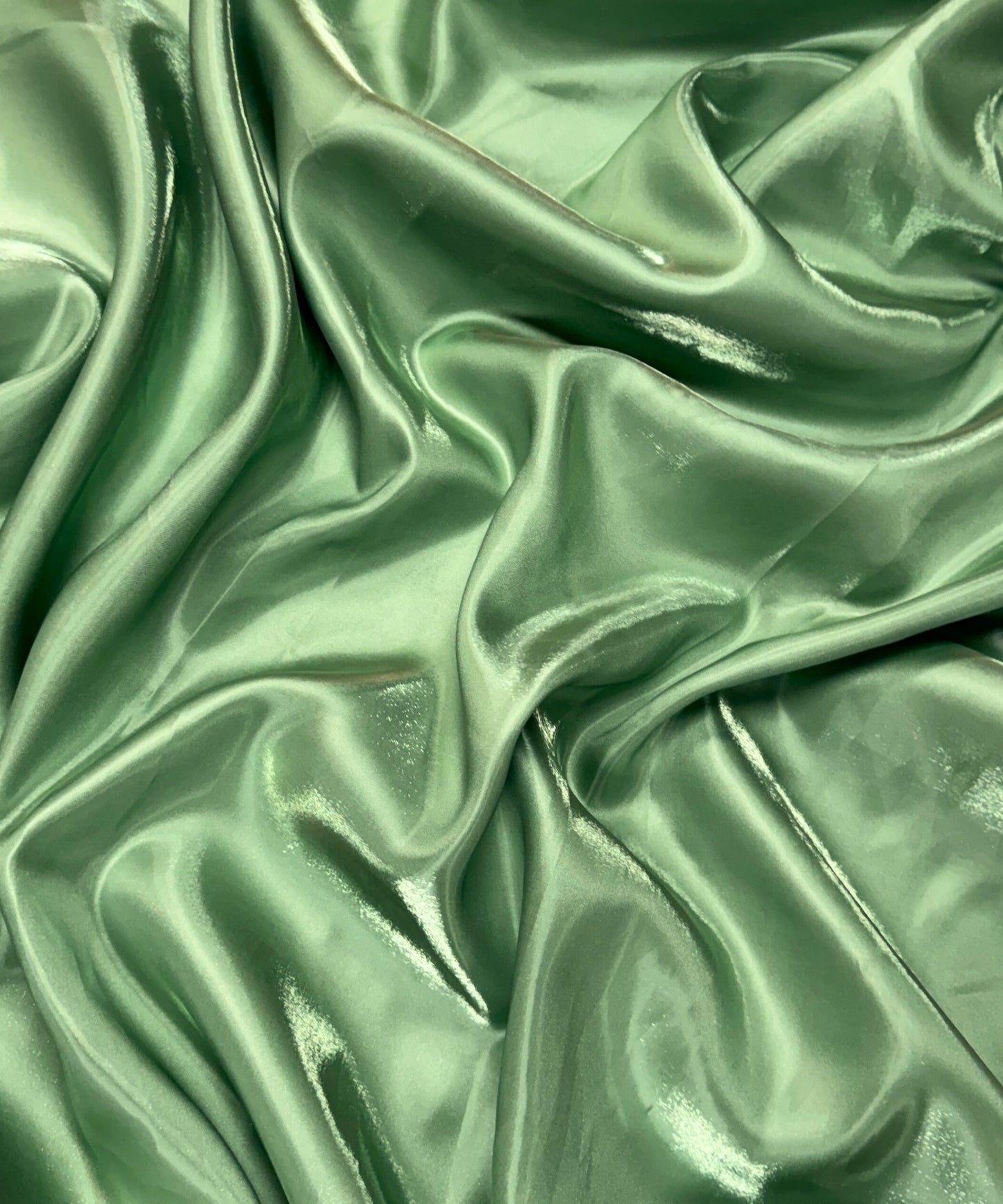 Sage green liquid bridal satin fabric with ultra-glossy finish, fluid drape, and silky smooth texture – perfect for gowns and elegant décor.