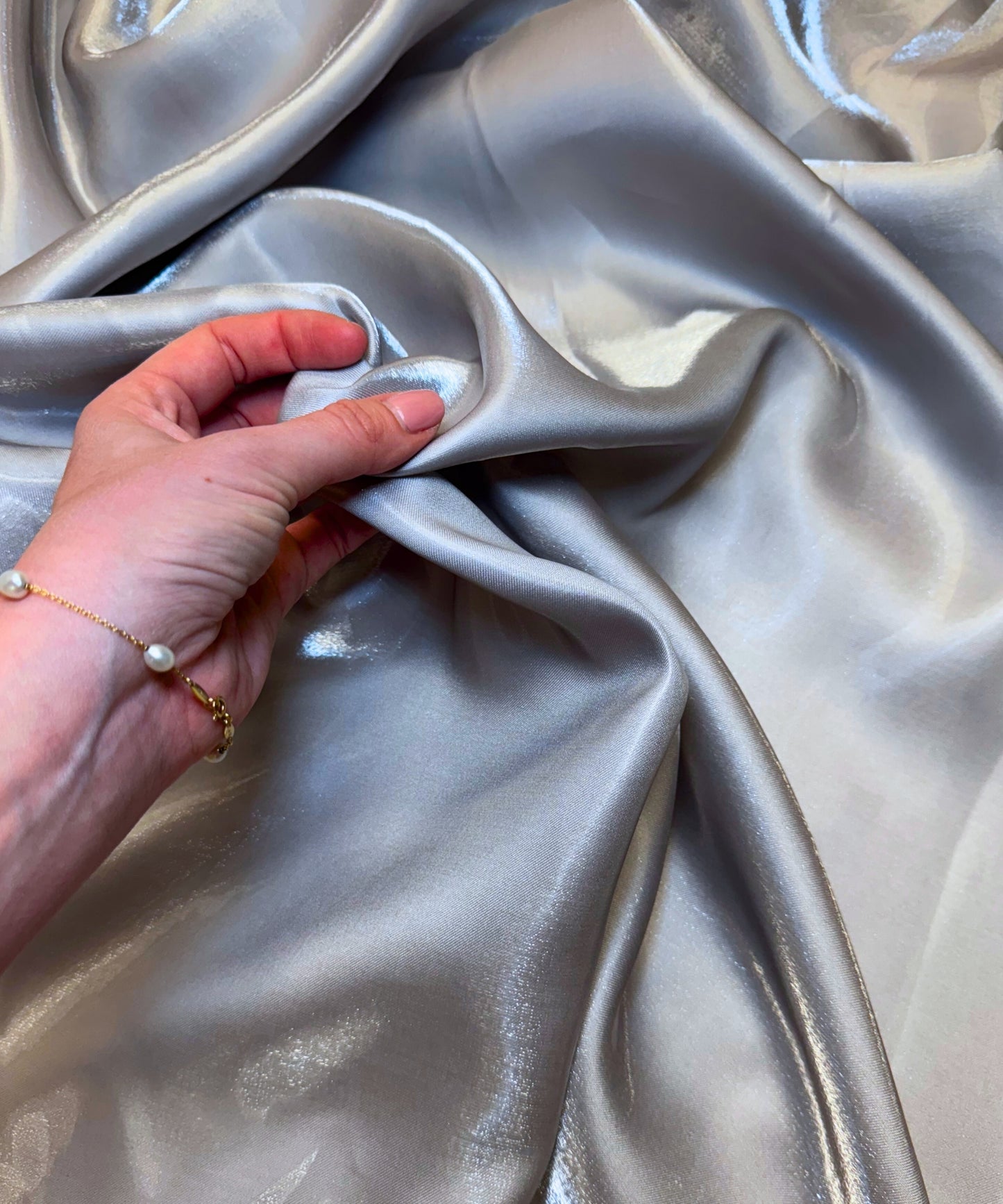 Silver liquid bridal satin fabric with ultra-glossy finish, fluid drape, and silky smooth texture – perfect for gowns and elegant décor.