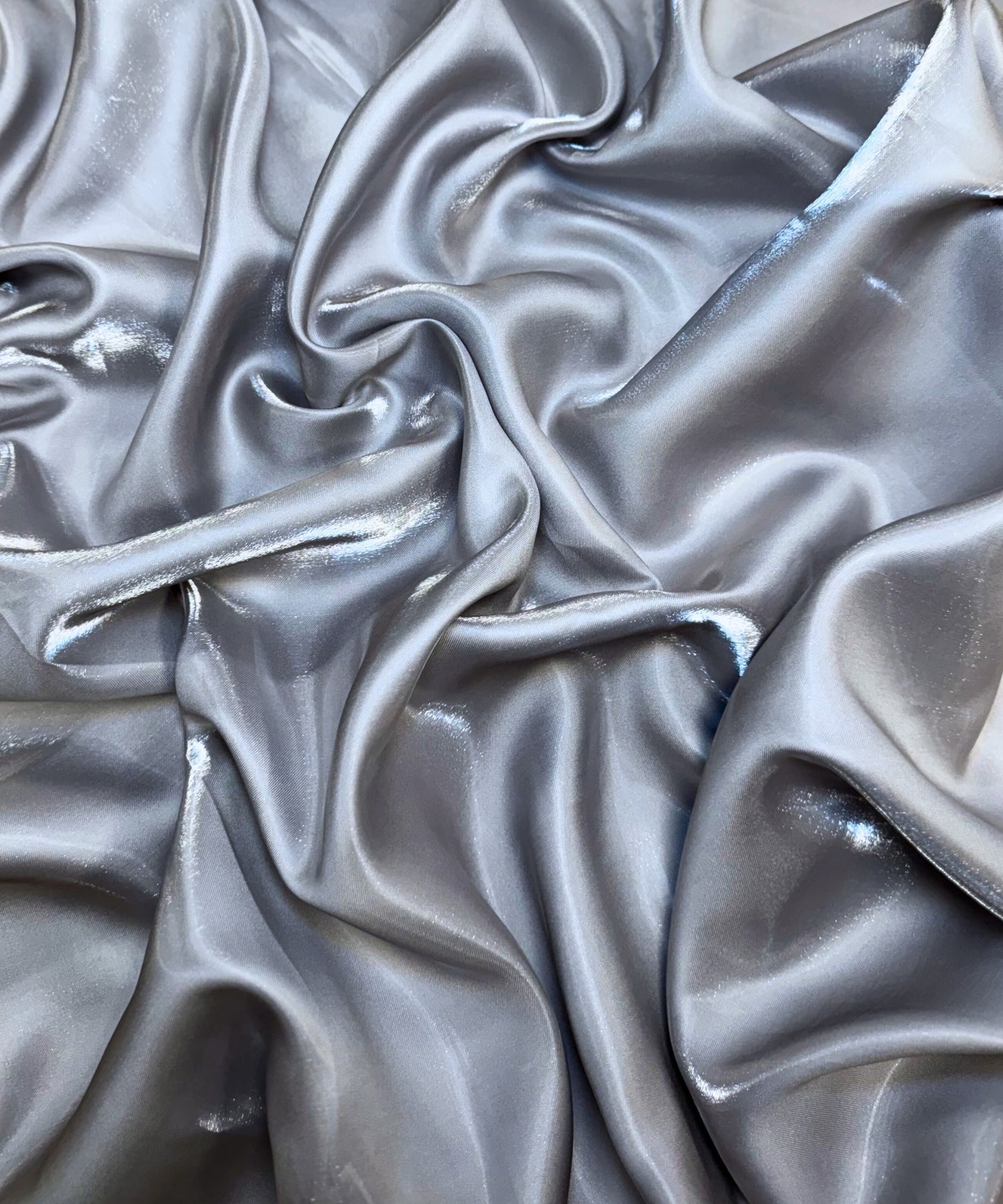 Silver liquid bridal satin fabric with ultra-glossy finish, fluid drape, and silky smooth texture – perfect for gowns and elegant décor.