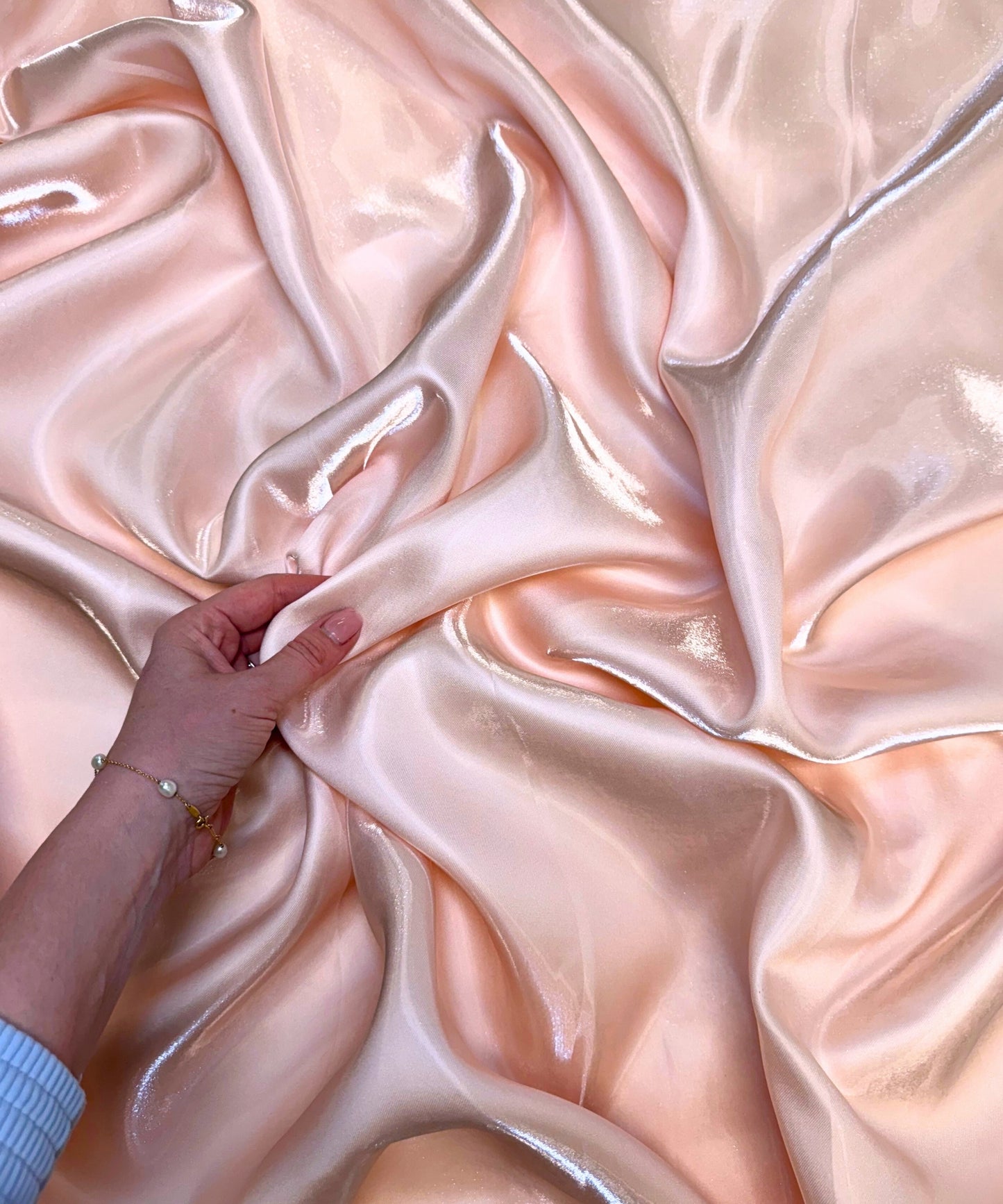 Blush liquid bridal satin fabric with ultra-glossy finish, fluid drape, and silky smooth texture – perfect for gowns and elegant décor.