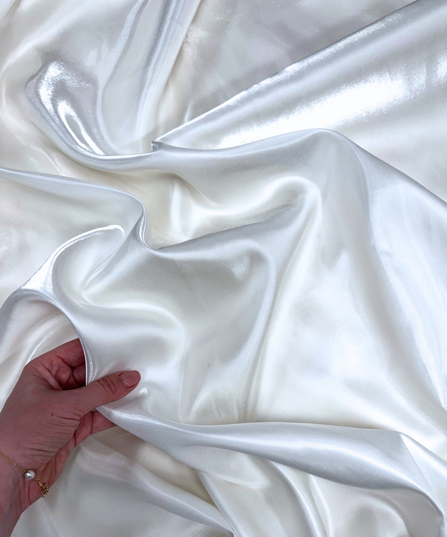 White liquid bridal satin fabric with ultra-glossy finish, fluid drape, and silky smooth texture – perfect for gowns and elegant décor.