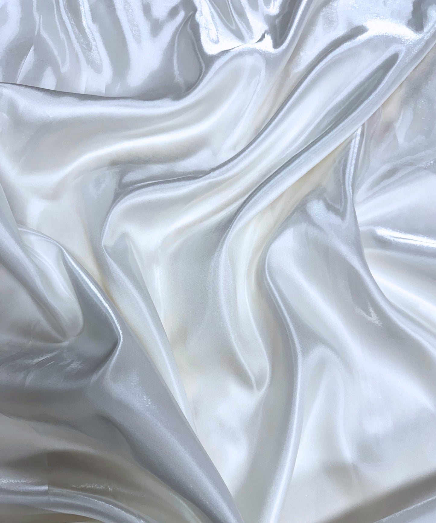 White liquid bridal satin fabric with ultra-glossy finish, fluid drape, and silky smooth texture – perfect for gowns and elegant décor.