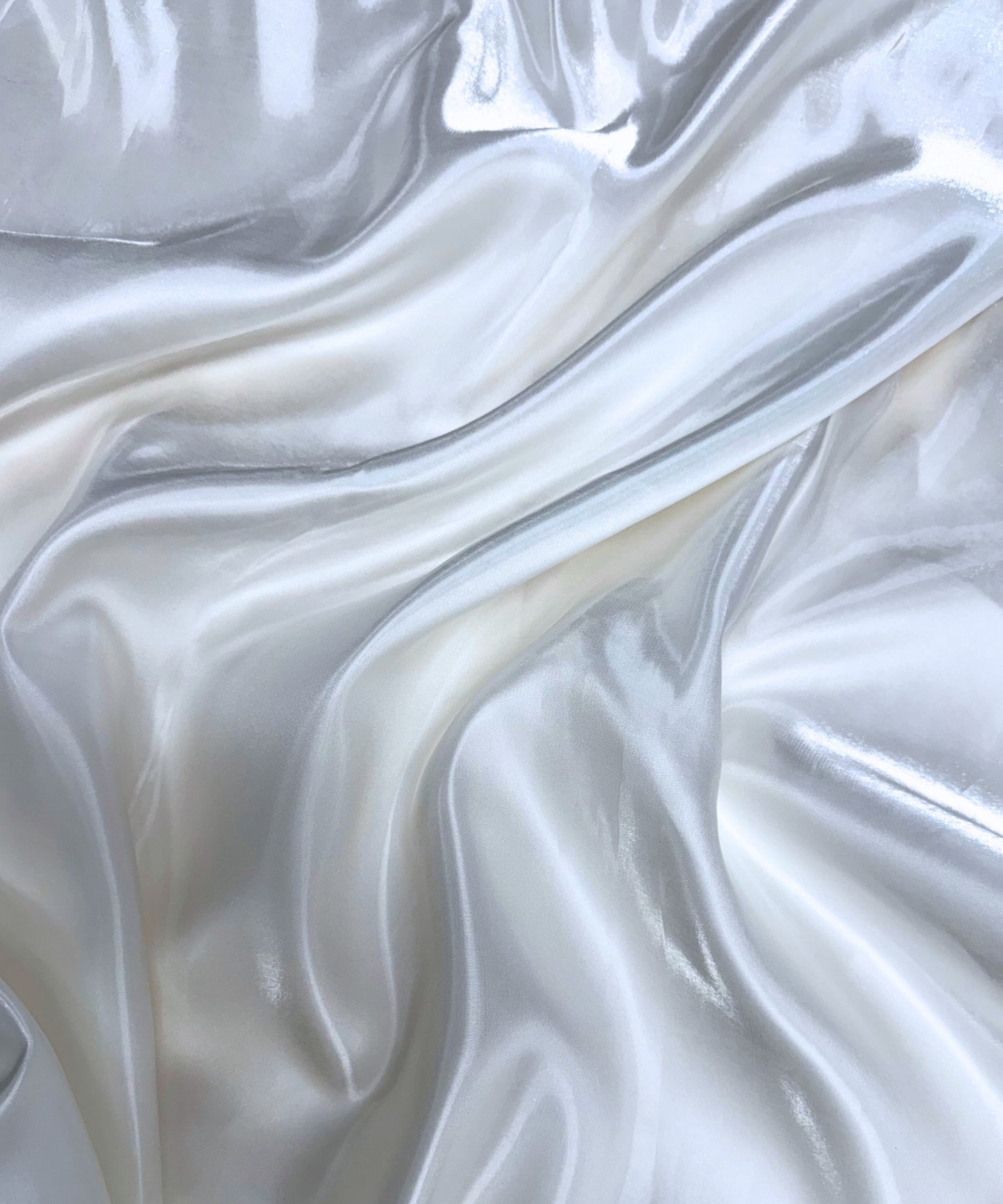 White liquid bridal satin fabric with ultra-glossy finish, fluid drape, and silky smooth texture – perfect for gowns and elegant décor.