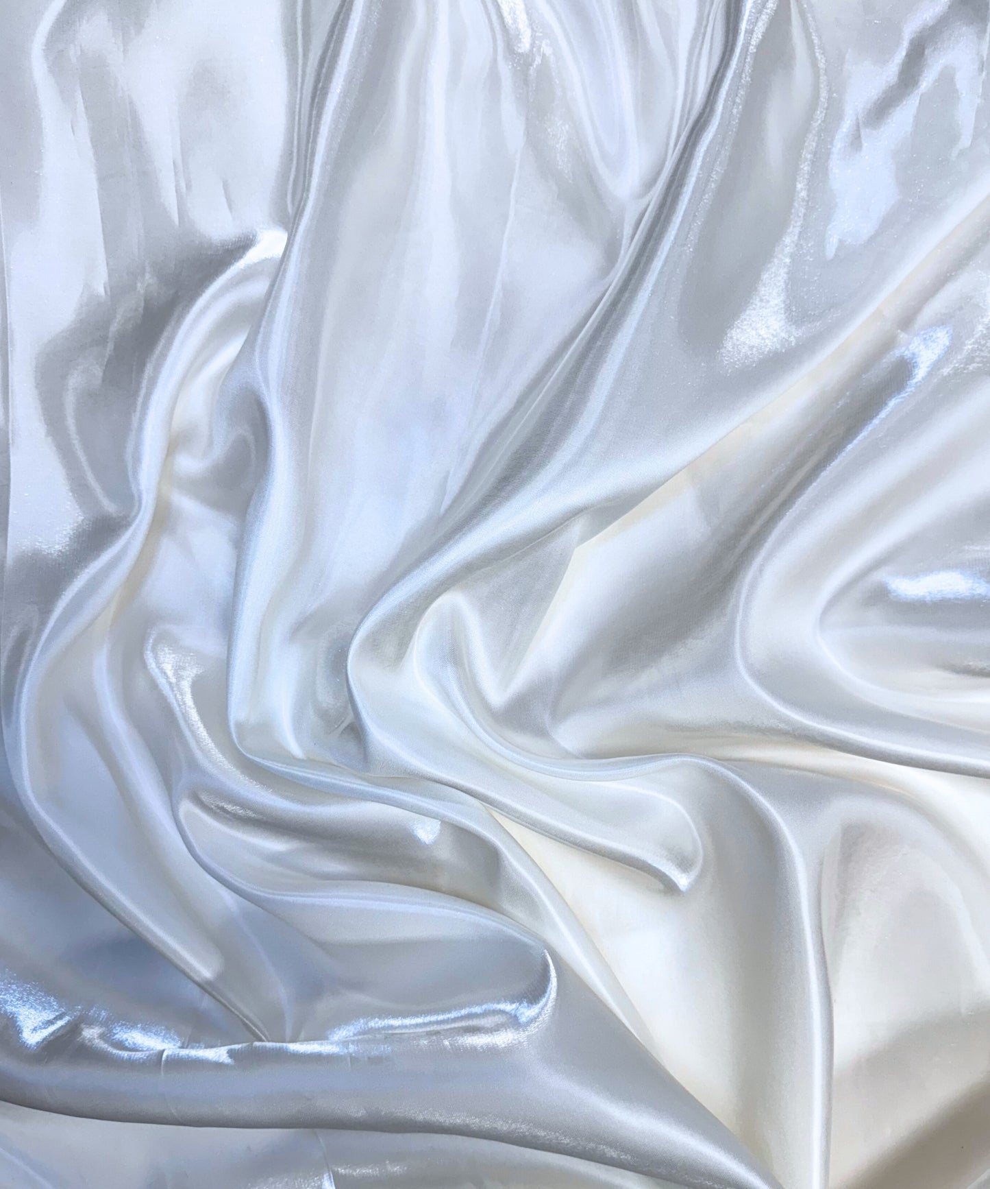White liquid bridal satin fabric with ultra-glossy finish, fluid drape, and silky smooth texture – perfect for gowns and elegant décor.