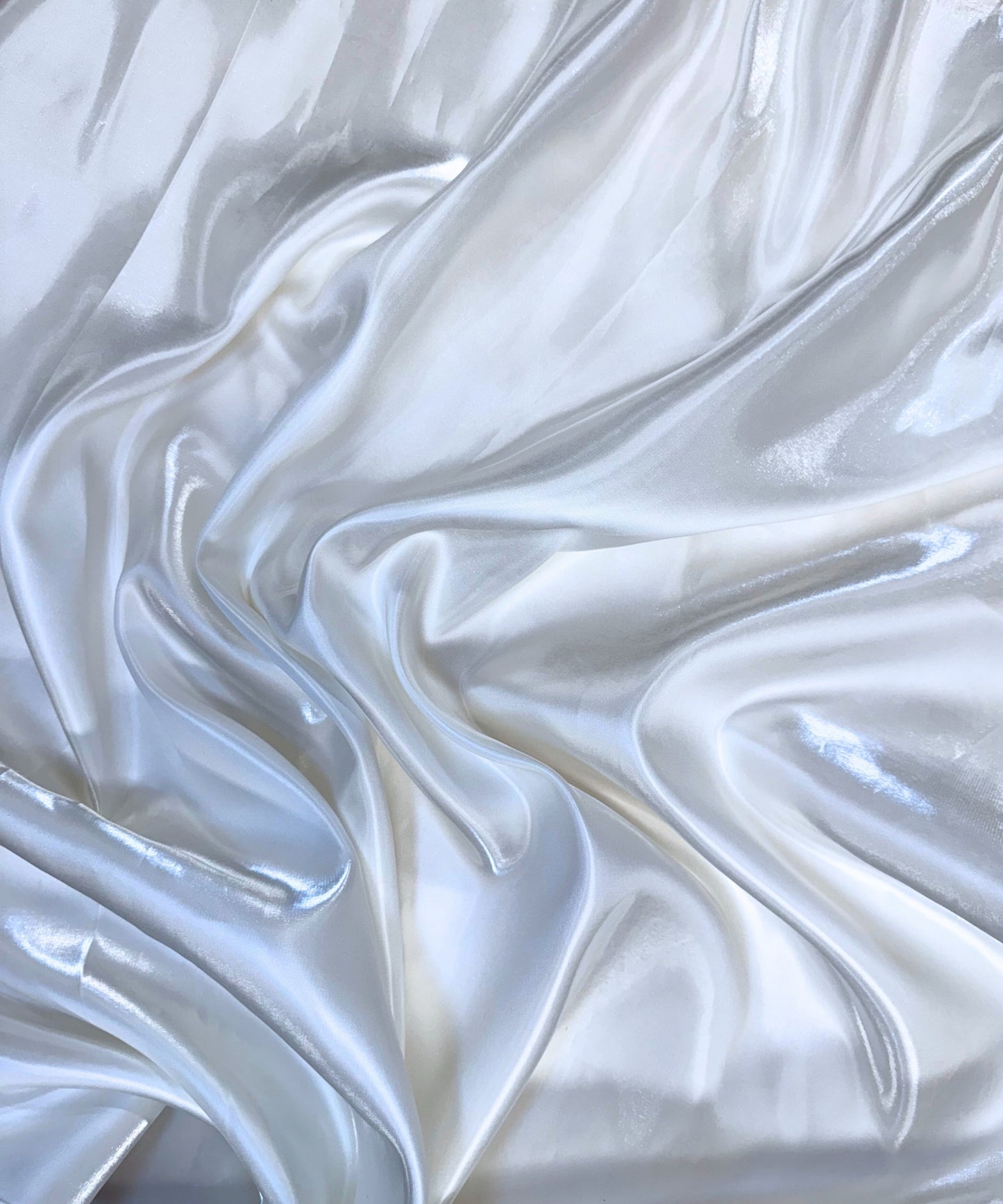 White liquid bridal satin fabric with ultra-glossy finish, fluid drape, and silky smooth texture – perfect for gowns and elegant décor.