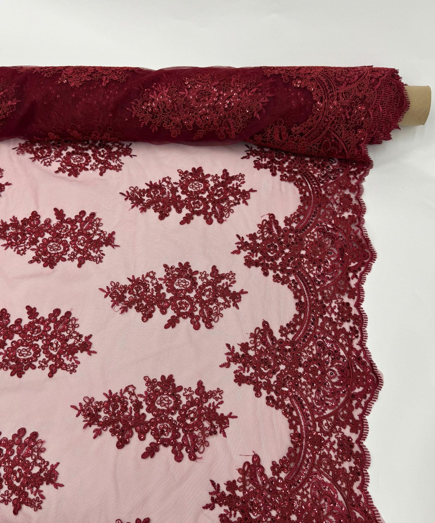 yard of burgundy floral lace fabric with gold embroidery and sequins, detailing the intricate floral patterns and the mesh texture.