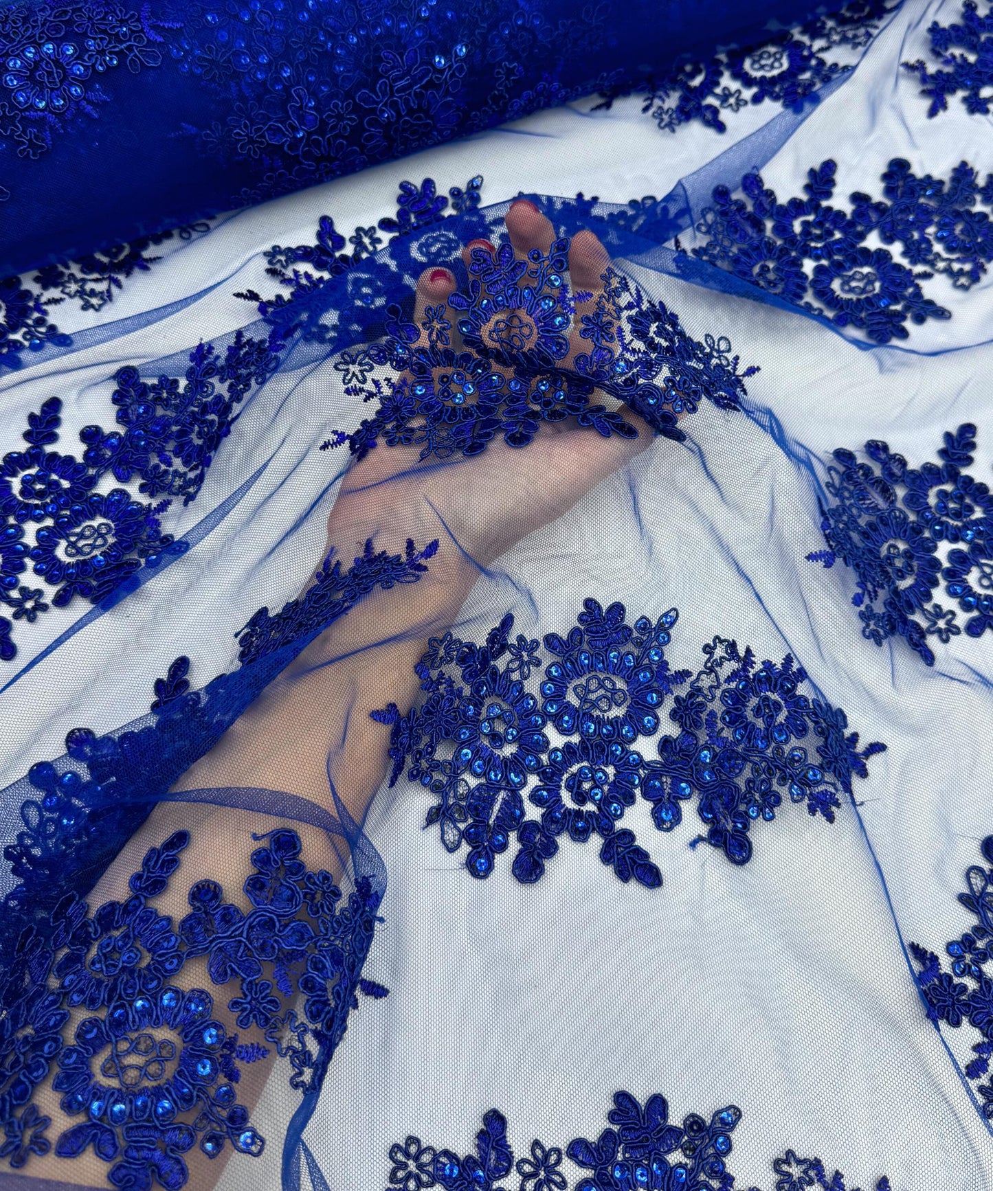yard of royal blue floral lace fabric with gold embroidery and sequins, detailing the intricate floral patterns and the mesh texture.