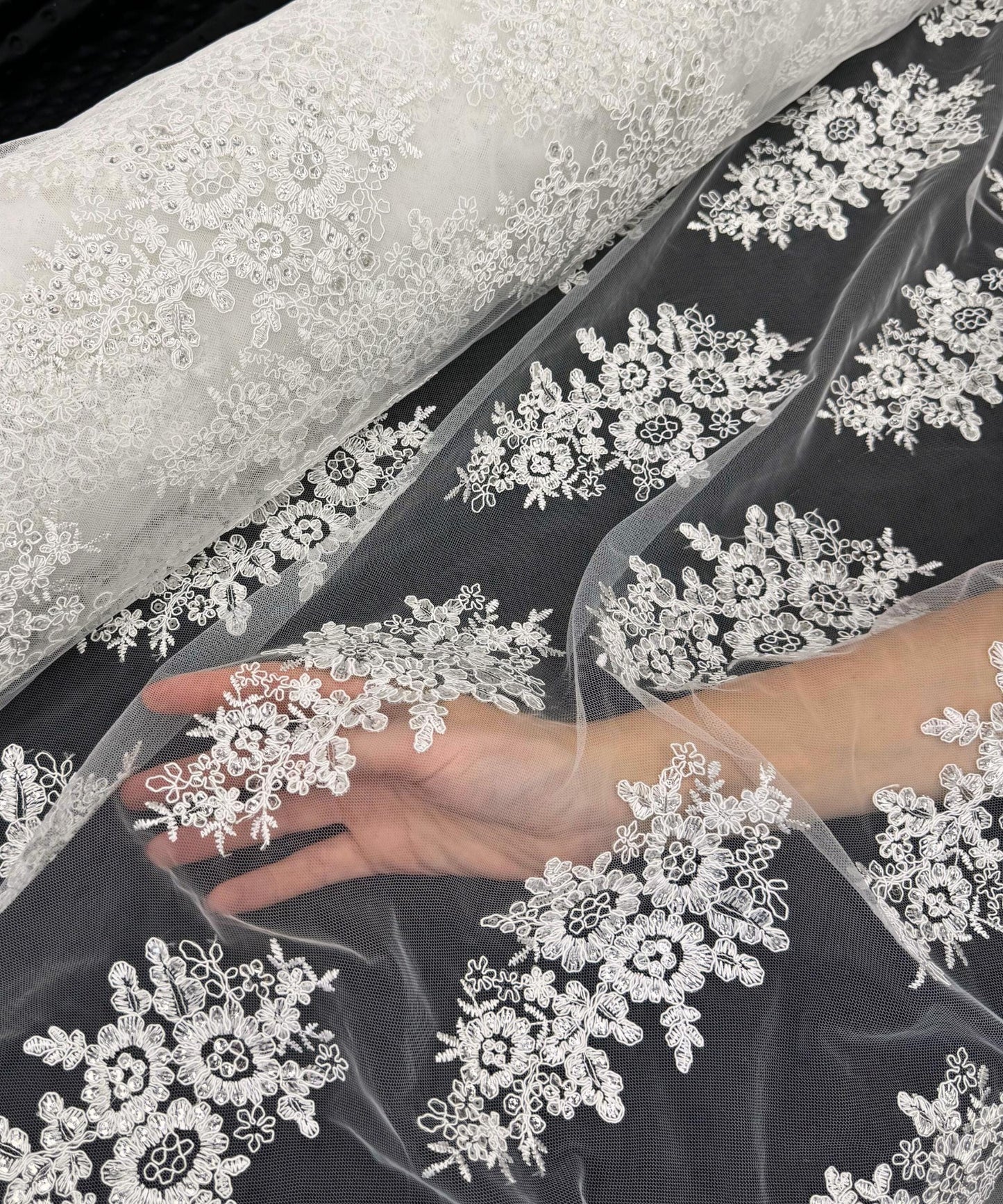yard of ivory floral lace fabric with gold embroidery and sequins, detailing the intricate floral patterns and the mesh texture.