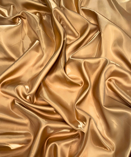 Gold liquid bridal satin fabric with ultra-glossy finish, fluid drape, and silky smooth texture – perfect for gowns and elegant décor.