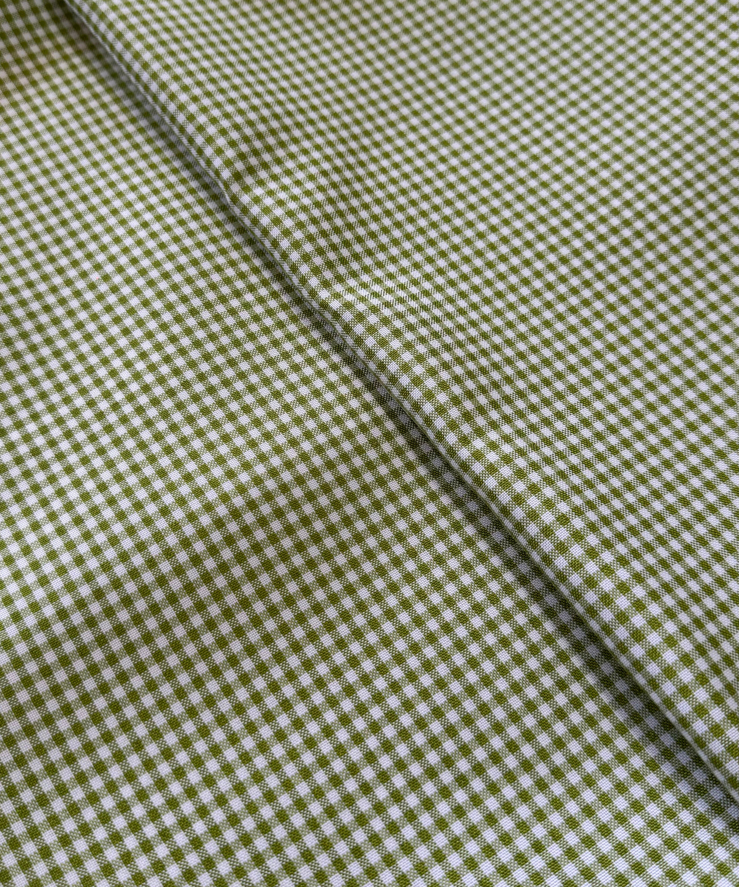 Close-up of green and white checkered fabric. Sage 1/8" Gingham Shirting Poplin