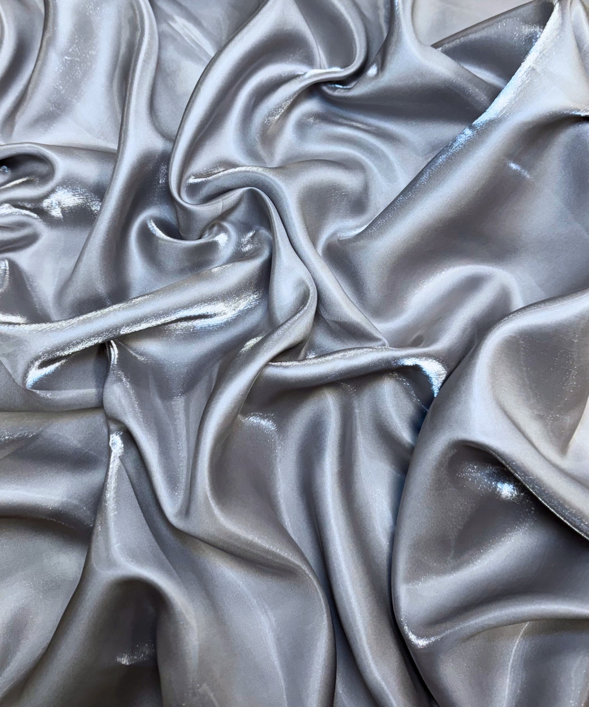 Silver liquid bridal satin fabric with ultra-glossy finish, fluid drape, and silky smooth texture – perfect for gowns and elegant décor.